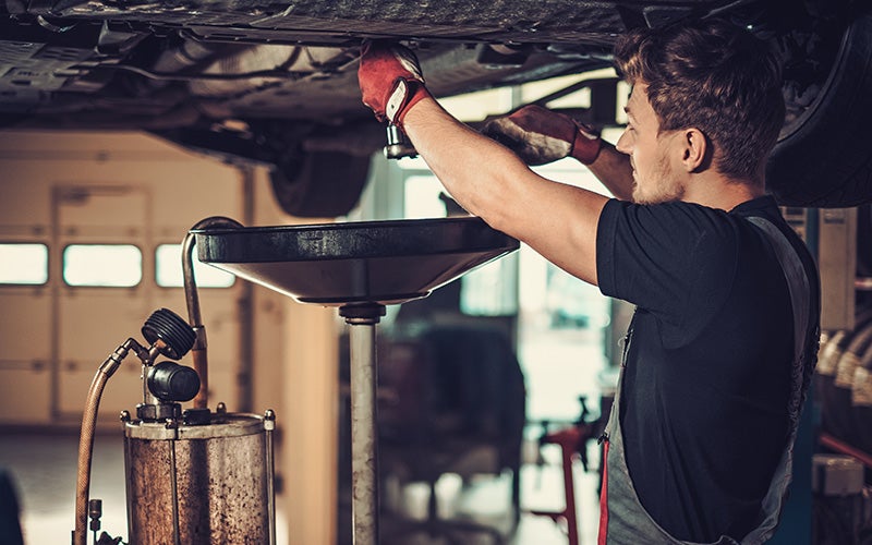 Service tech working under a car during an oil change
